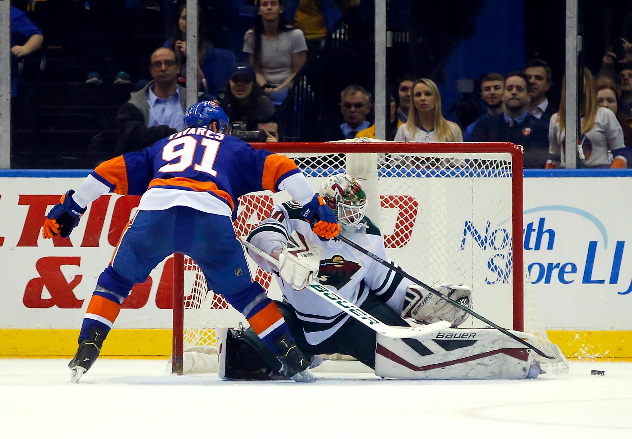 New York Islanders center John Tavares (91) is stopped as he tried score by wrapping the puck past Minnesota Wild goalie Devan Dubnyk on the last shot of a shootout in an NHL hockey game Tuesday, March 24, 2015, in Uniondale, N.Y. Minnesota won 2-1. (AP Photo/Paul Bereswill)