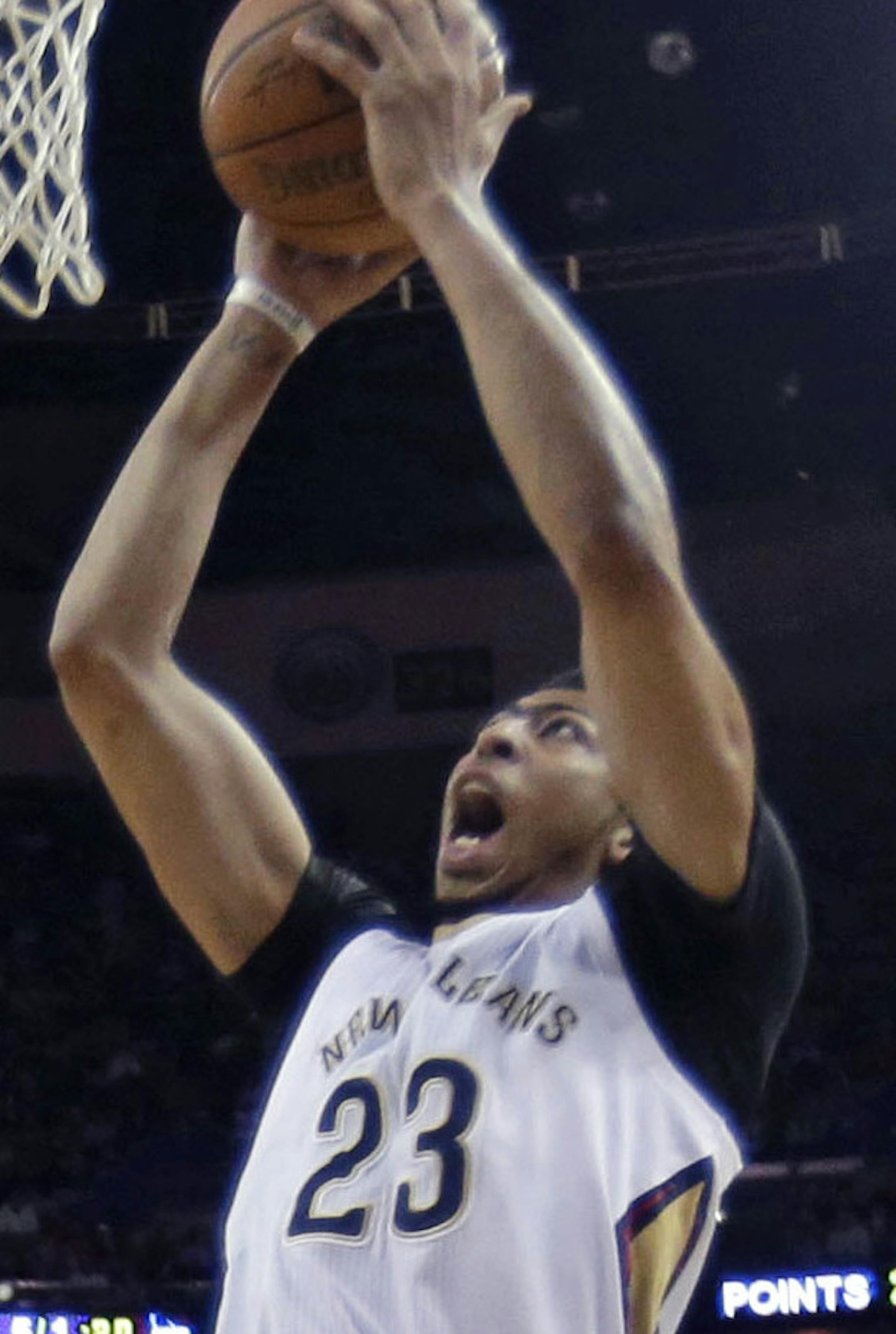 New Orleans Pelicans forward Anthony Davis (23) goes to the basket between Phoenix Suns forward Markieff Morris (11) and forward T.J. Warren (12) in the first half of an NBA basketball game in New Orleans, Friday, April 10, 2015. The Pelicans won 90-75. (AP Photo/Gerald Herbert)