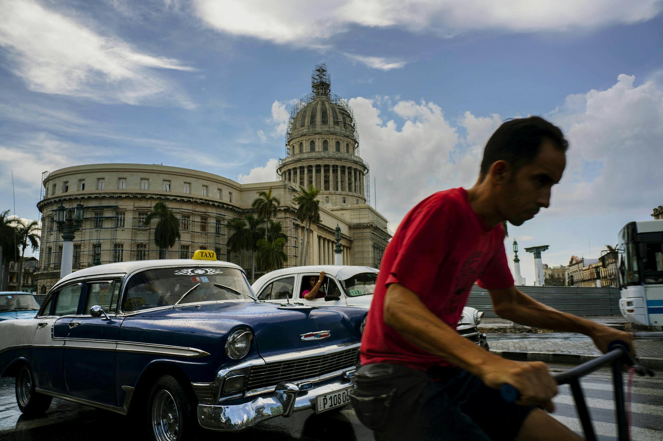 FILE - In this July 15, 2016 file photo, a man cycles alongside taxi drivers near the Capitol building in Havana, Cuba. A rare poll of Cuban public opinion taken in late 2016 has found that most Cubans approve of normal relations with the United States and large majorities want more tourism and private business ownership. (AP Photo/Ramon Espinosa, File) ORG XMIT: MIN2017042814300321