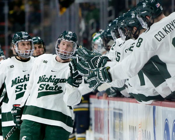 Michigan State forward Mitchell Lewandowski celebrates with teammates after scoring against Michigan during the third period of an NCAA college hockey