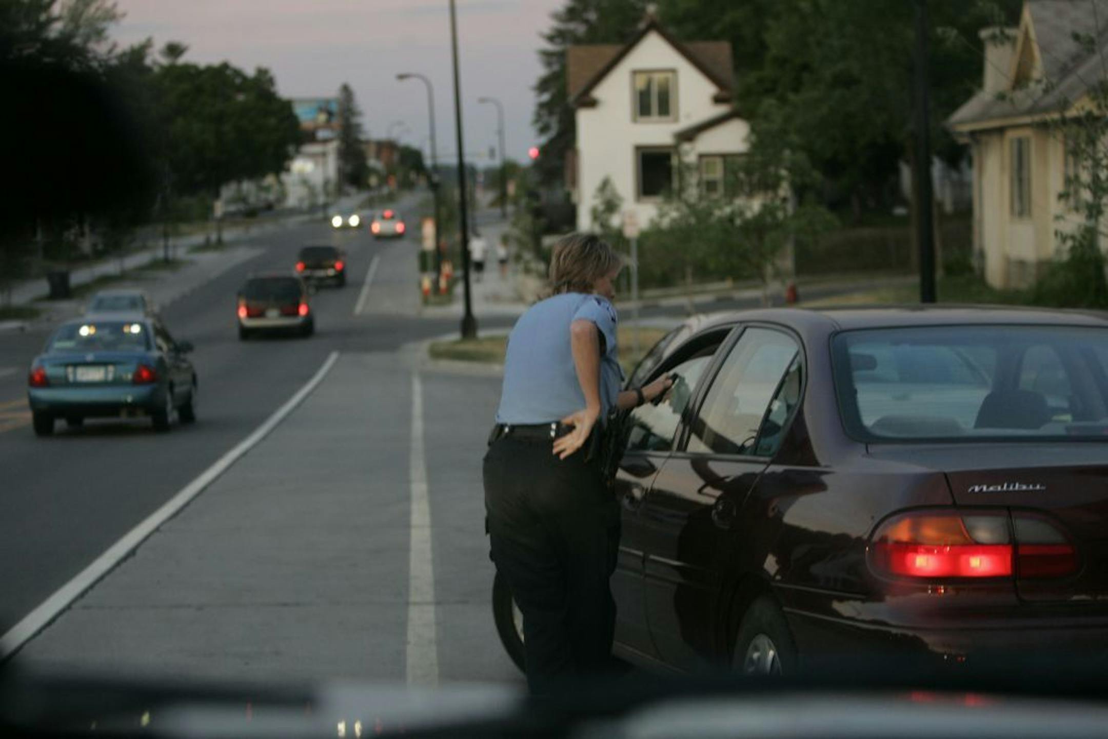 DAVID JOLES � djoles@startribune.com Minneapolis, MN - June 27, 2007 - Minneapolis police officer Lora Hanks outside a vehicle on a traffic stop on Lowry Ave. N near Emmerson. Shortly after this photo was taken the suspect fled, and officer Hanks stepped back to avoid being hit. Hanks then ran back to her police vehicle and radioed in to dispatch. The suspect led police on a high speed pursuit that ended in a collision with another vehicle near N. Lowry Ave. and Stinson Blvd. Two passengers in t
