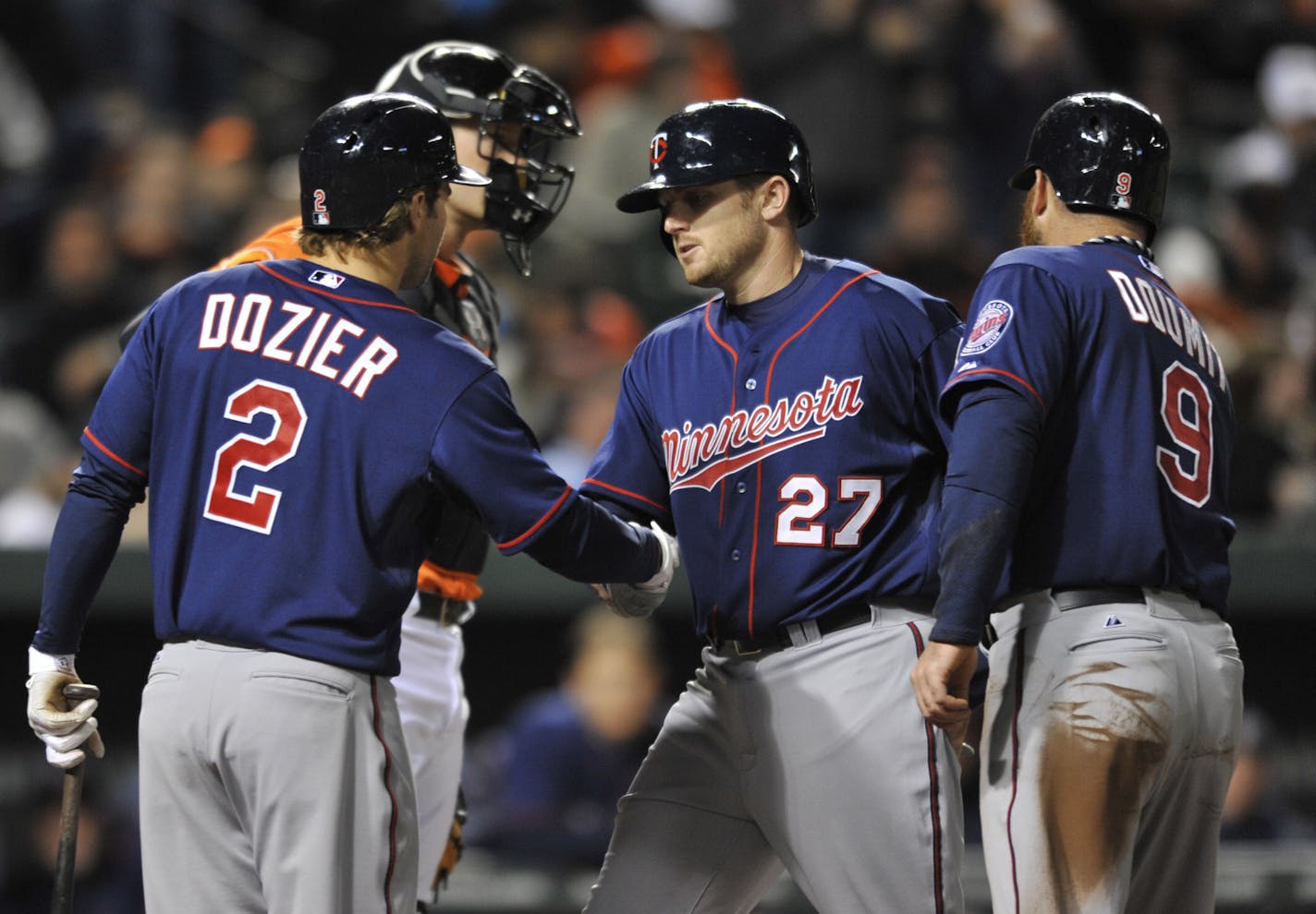 Minnesota Twins' Chris Parmalee, (27) is congratulated by Brian Dozier (2) and Ryan Doumit (9) after hitting a two-run home run against the Baltimore Orioles in the third inning of a baseball game on Saturday, April 6, 2013 in Baltimore. (AP Photo/Gail Burton)