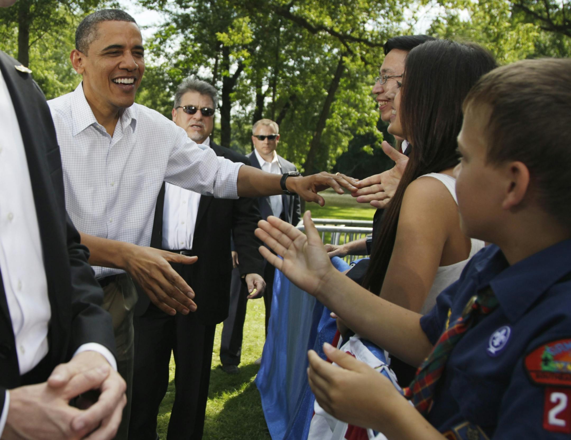 President Barack Obama shakes hands as he arrives to speak during a town hall meeting at Lower Hannah's Bend Park in Cannon Falls, Minn., Monday, Aug. 15, 2011.