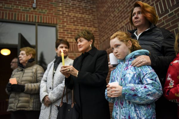 Sarah Matlock, of St. Paul, stood with her daughter, Teyla, 8, outside the doors of the Shir Tikvah temple Friday night greeting members of the Jewish