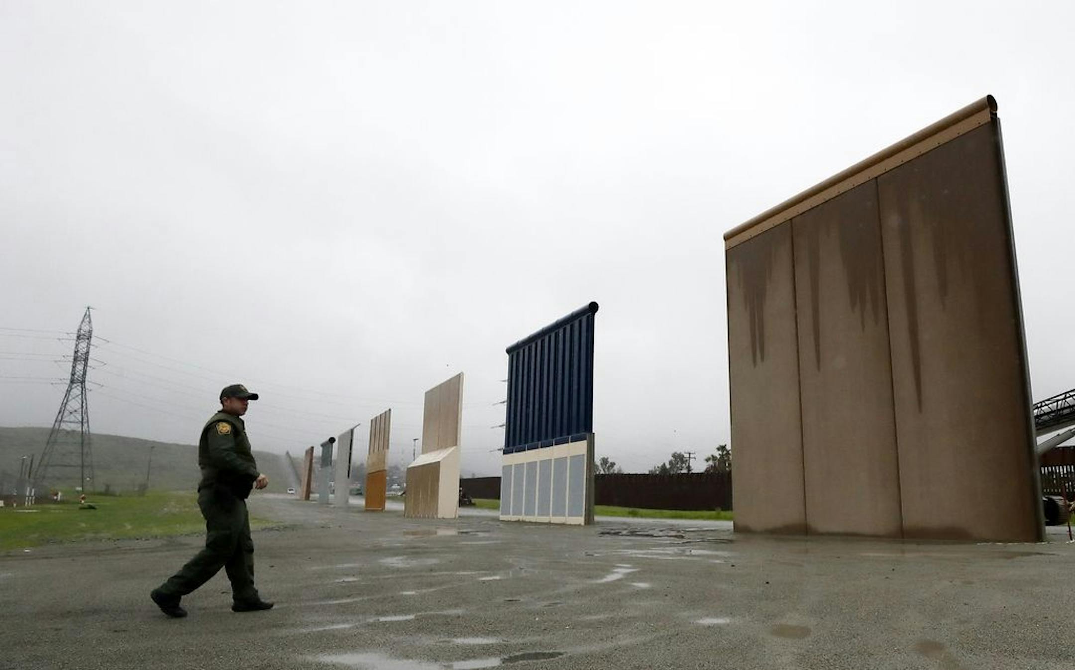 FILE - In this Feb. 5, 2019 file photo a Border Patrol agent walks towards prototypes for a border wall in San Diego. The Trump administration on Wednesday, Feb. 27 plans to demolish eight prototypes of the president's prized border wall that the government built near San Diego one year ago.