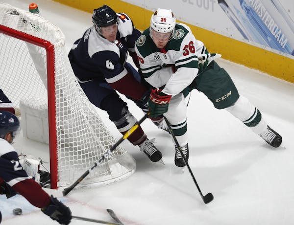 Minnesota Wild defenseman Nick Seeler, right, drives past Colorado Avalanche defenseman Tyson Barrie to wrap around the net for a shot in the first pe