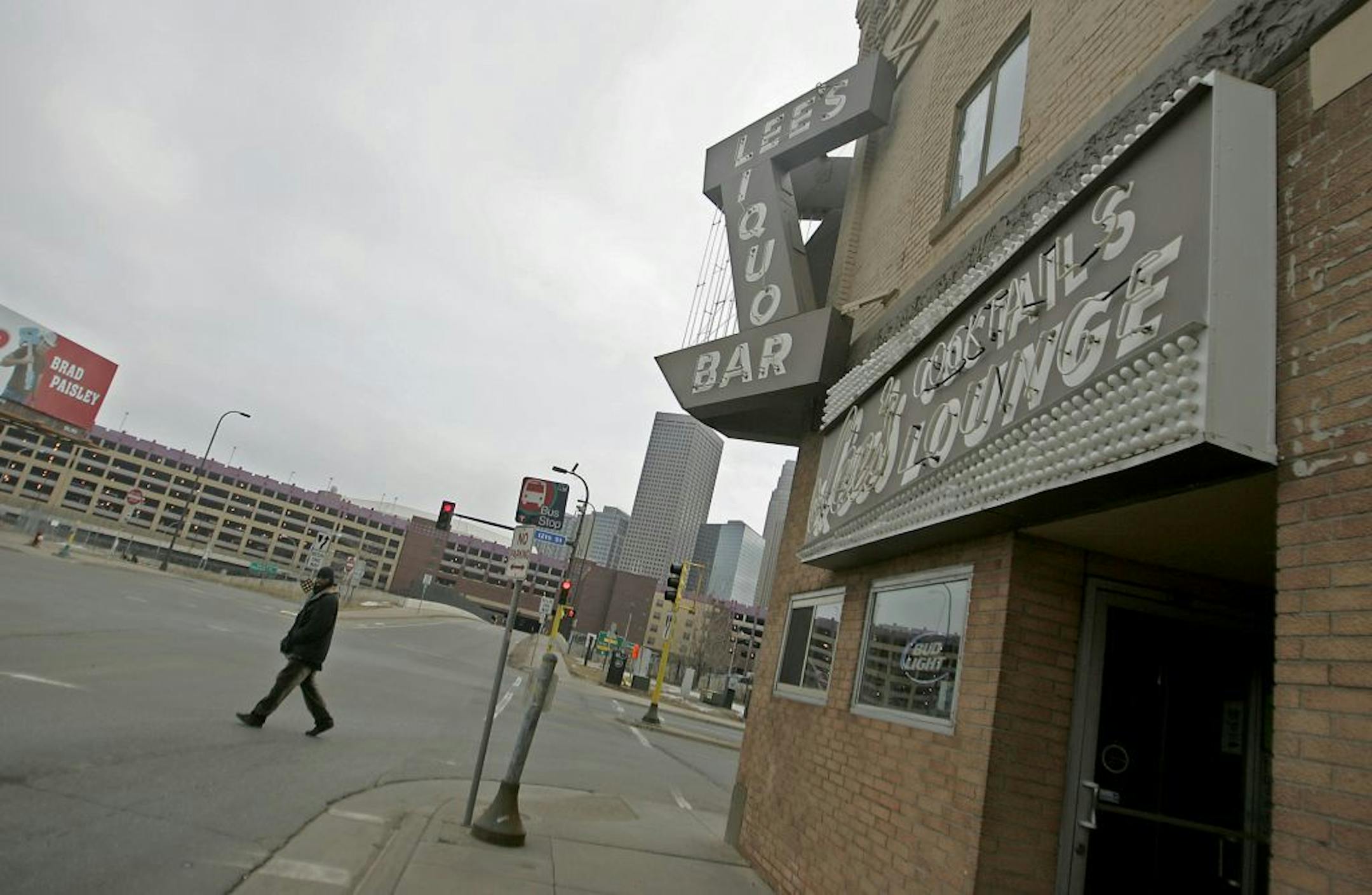 ELIZABETH FLORES • eflores@startribune.com February 13, 2009 - Minneapolis, MN - With the new Twins' stadium looming in the background, a pedestrian made his way near the famous Lee's Liquor Lounge. For Lee's Liquor Lounge owner, Lou Sirion, it looked like like the new twins stadium was going to be a blessing. Instead, it might be a mess. It looks like the twins are going to come and take his parking lot. Lee's is named after Sirion's wife.