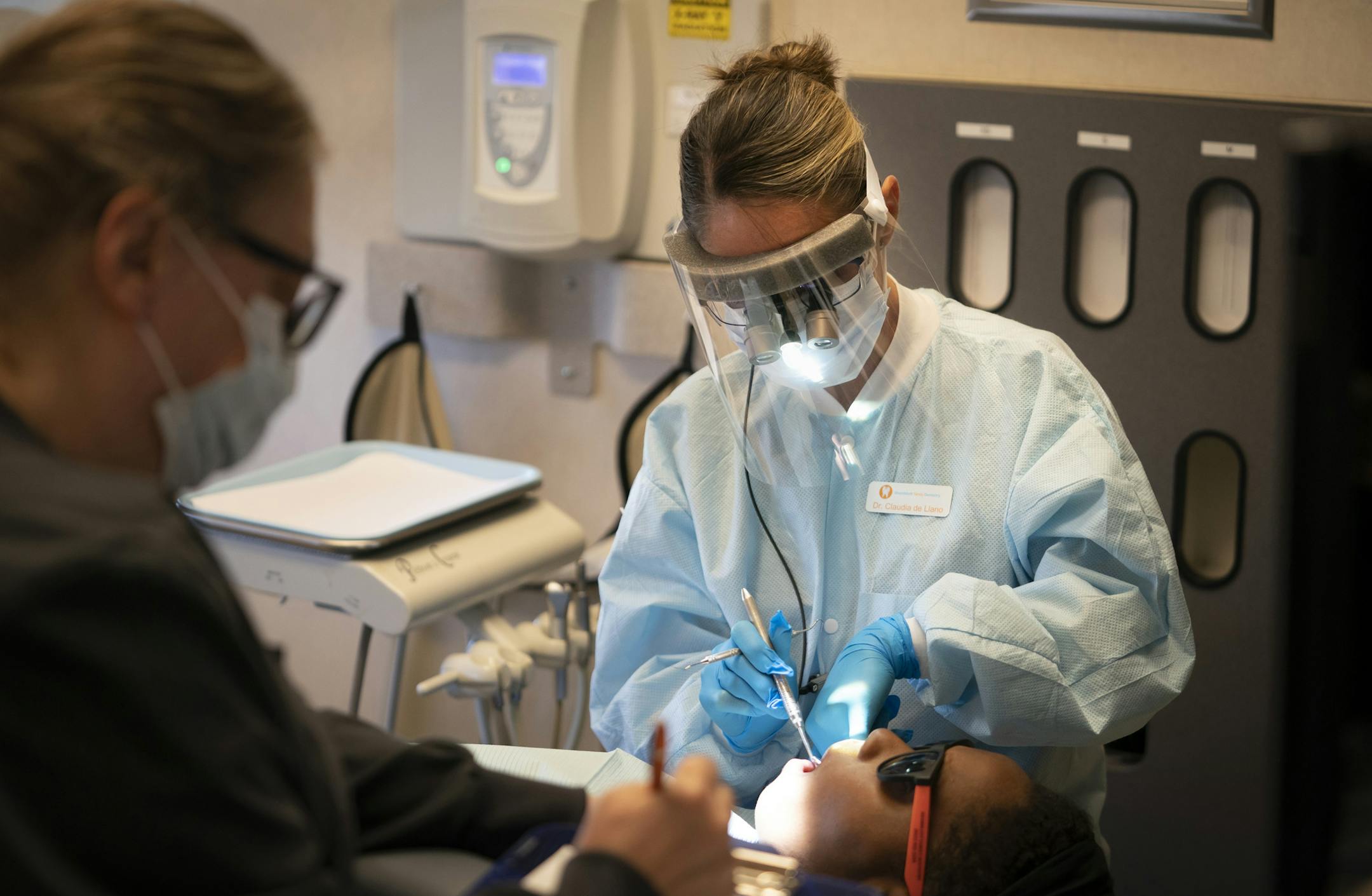 Dr. Claudia de Liano tested patient Charity Stevson's (CQ) teeth for sensitivity during an appointment at Shamblott Family Dentistry in Hopkins, Minn., on Tuesday, May 12, 2020. At left was dental assistant Amy Knoll taking notes. ] RENEE JONES SCHNEIDER ¥ renee.jones@startribune.com Shamblott Family Dentistry is taking extreme precaution as it opens back after the Covid-19 shutdown by double masking the doctors and hygienists, wearing plastic shields, taking customers temperatures when they arr