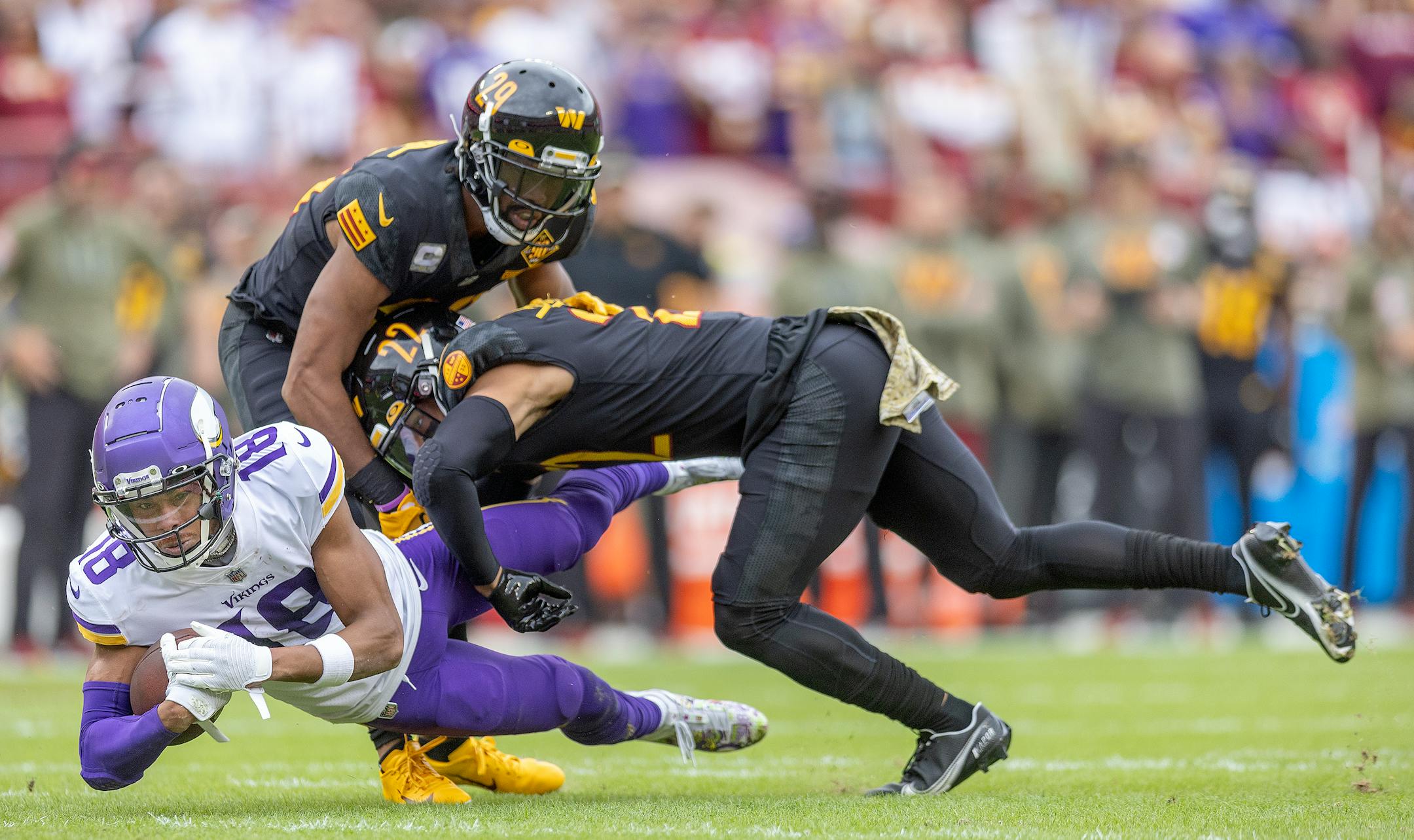 Minnesota Vikings wide receiver Justin Jefferson (18) makes a grab for a first down despite pressure from Commanders safety Darrick Forrest (22), right, and Commanders cornerback Kendall Fuller (29) in the first quarter.