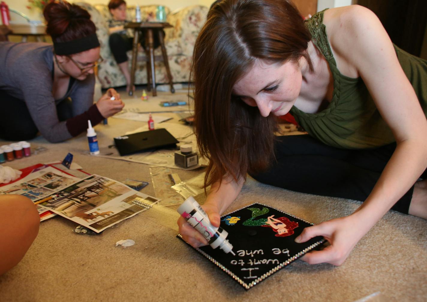 Hanna DeGroot wrote out the words on her friend Olivia Martinson's graduation cap because she had the steadier hand. ] (KYNDELL HARKNESS/STAR TRIBUNE) kyndell.harkness@startribune.com A party at Hanna DeGroot's apartment, where she and some gal pals will be decorating their graduation caps in Minneapolis Min., Friday, May 8, 2015.