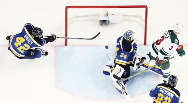 The St. Louis Blues' David Backes sweeps in behind goaltender Jake Allen to prevent the puck from crossing the goal line against the Minnesota Wild in
