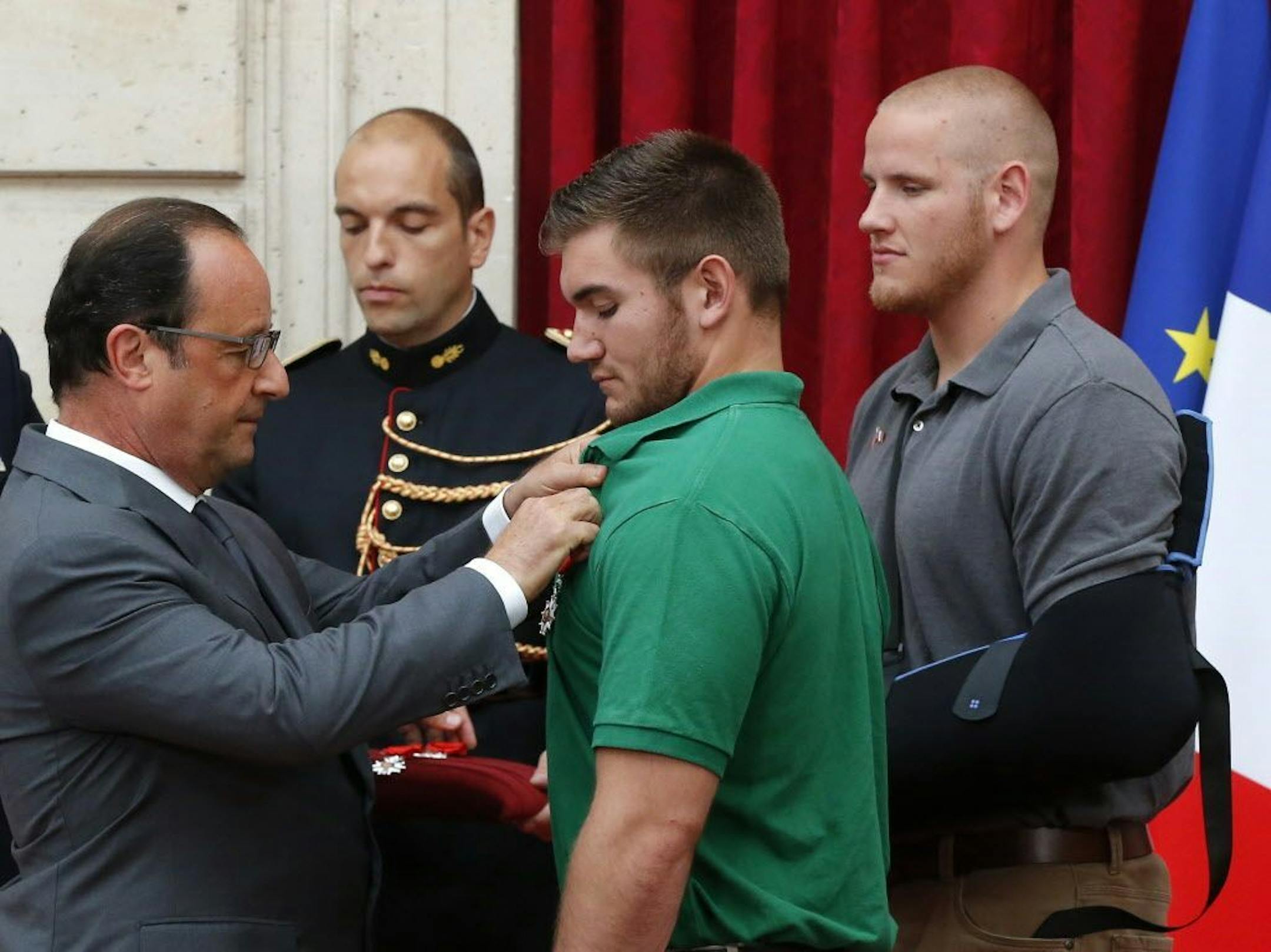 French President Francois Hollande, left, awards the Legion of Honor to Alek Skarlatos a U.S. National Guardsman from Roseburg, Oregon, while U.S. Airman Spencer Stone, right, looks on at the Elysee Palace, Monday Aug. 24, 2015 in Paris.