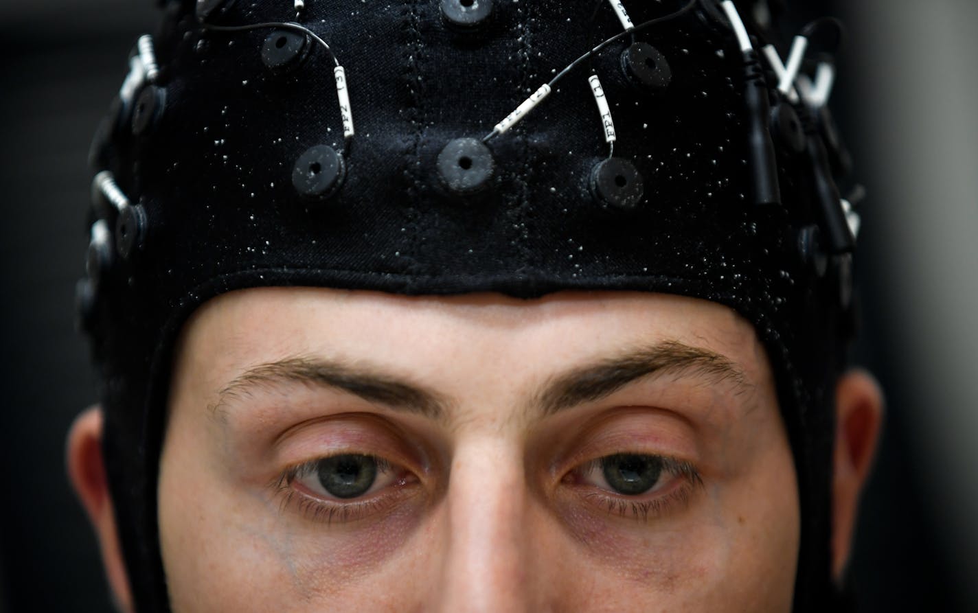 Brad Edelman, biomedical engineering graduate student, donned a high intensity EEG (electroencephalography) cap that he uses to control a robotic arm being developed at the University of Minnesota. ] (AARON LAVINSKY/STAR TRIBUNE) aaron.lavinsky@startribune.com University of Minnesota researchers have developed an non-invasive technology that will allow people to control a robotic arm using their minds. We photograph Jianjun (Steve) Meng, biomedical engineering postdoctoral researcher, and Brad E