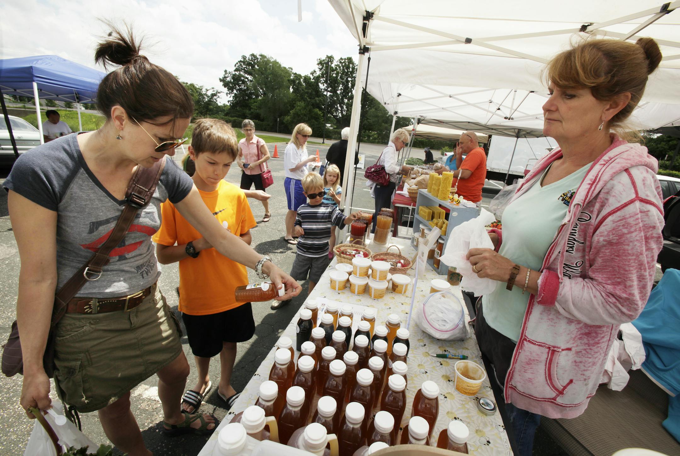 Wendy Barnum and her son Ian Barnum of Lakeville look at the honey that Arlene Hill of Aspen Ridge Honey Farm had on display at the farmers market in Rosemount, MN. June 18, 2013. ] JOELKOYAMA‚Ä¢joel koyama@startribune.com The farmers market in Rosemount, MN. June 18, 2013. ] JOELKOYAMA‚Ä¢joel koyama@startribune.comAfter a late spring and a rainy and cold start to the farmers' market season, we check in to see how the bad luck is affecting south metro markets, a