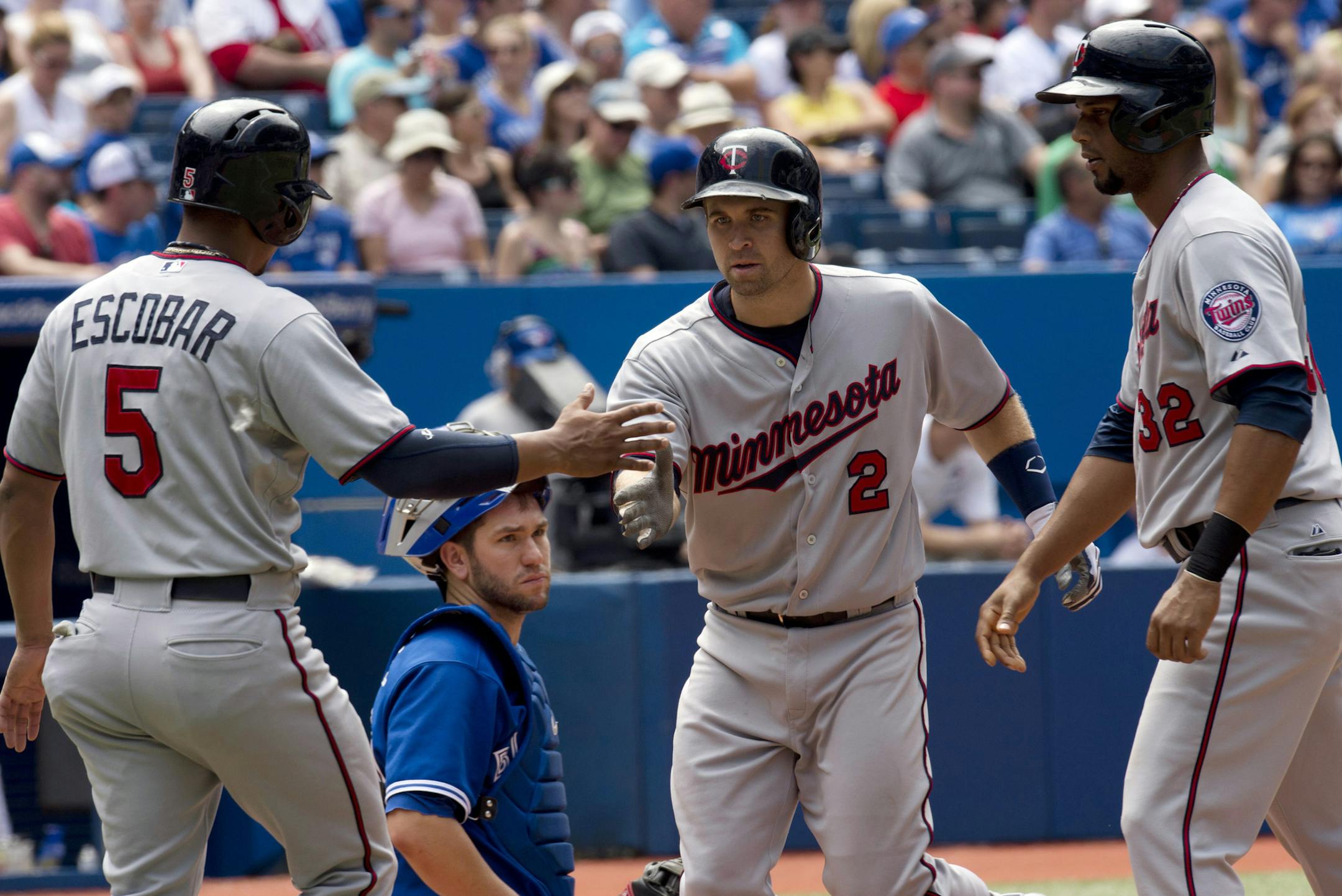 Toronto Blue Jays catcher Josh Thole watches as Minnesota Twins' Brian Dozier (2) is congratulated by teammates Eduardo Escobar (5) and Aaron Hicks (32) after scoring them on his three-run home run during the seventh inning of a baseball game in Toronto on Saturday, July 6, 2013. (AP Photo/The Canadian Press, Frank Gunn)