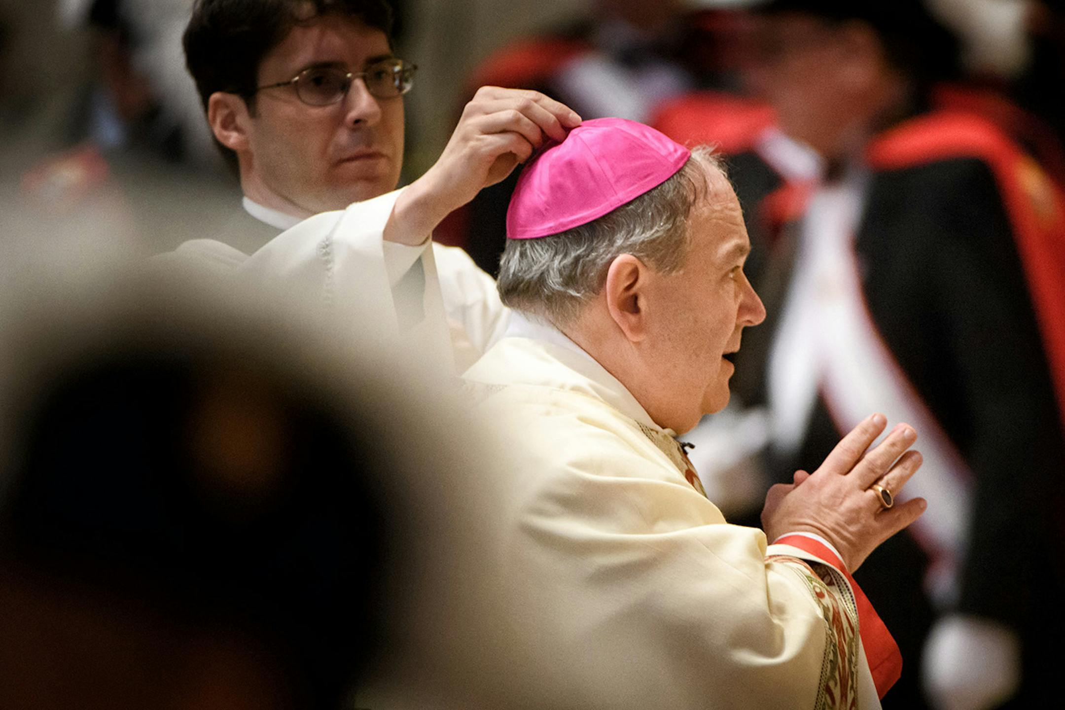 An aide adjusted Archbishop Bernard Hebda's small skull-cap called a zuchetto worn under his bishop's miter.