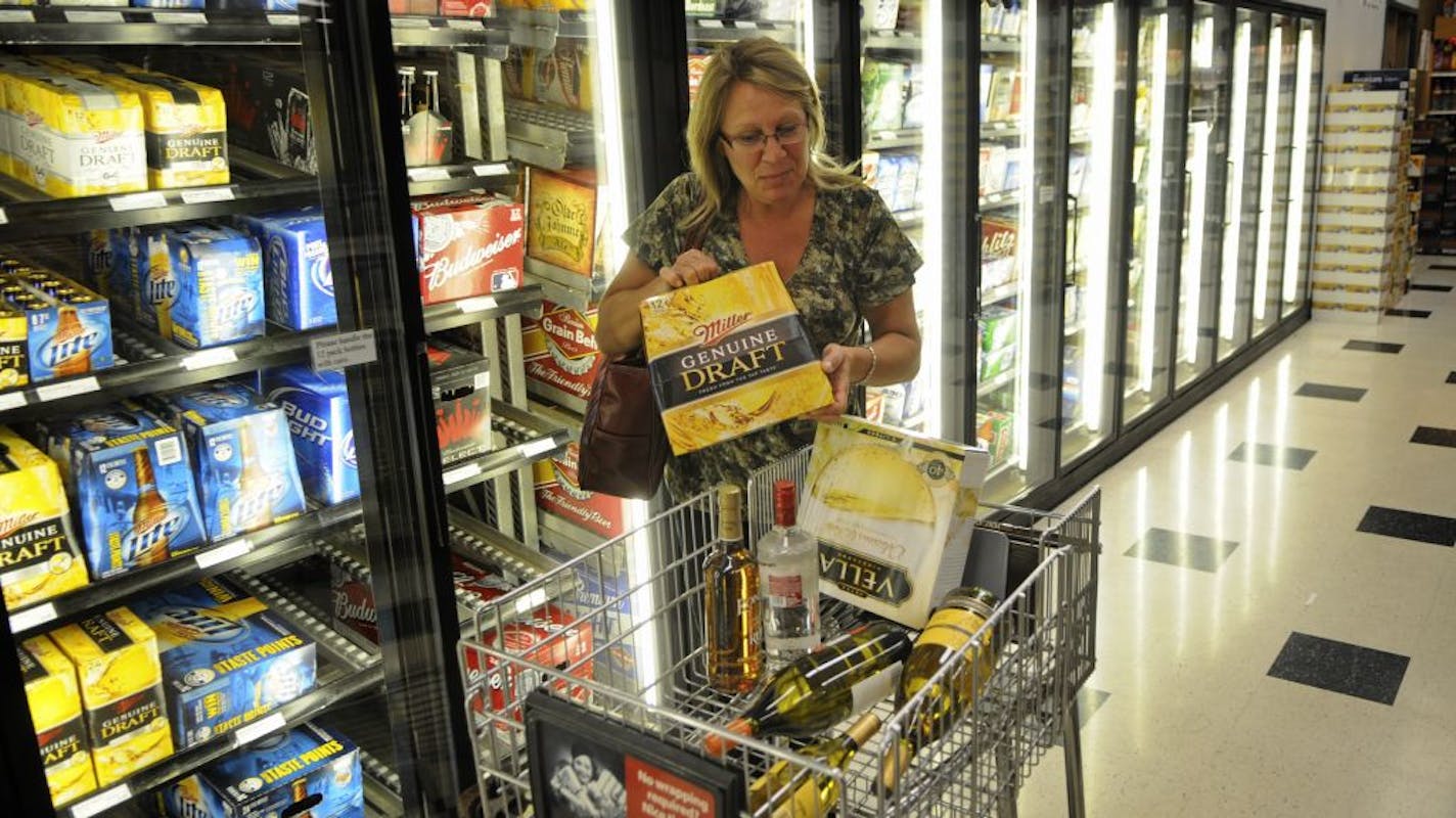 Stocking up: Diane O'Brien of New Brighton grabbed a 12-pack of Miller Genuine Draft on Wednesday afternoon from a cooler at Surdyk's in Minneapolis. Because of expired licenses that can't be renewed during the state government shutdown, MillerCoors has been ordered to stop distributing 39 brands of beer in the state. The brewing giant is vowing to fight.