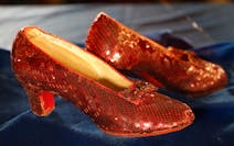 A pair of red women's slippers adorned with sparkles and a tiny bow toward the toe