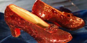 A pair of red women's slippers adorned with sparkles and a tiny bow toward the toe