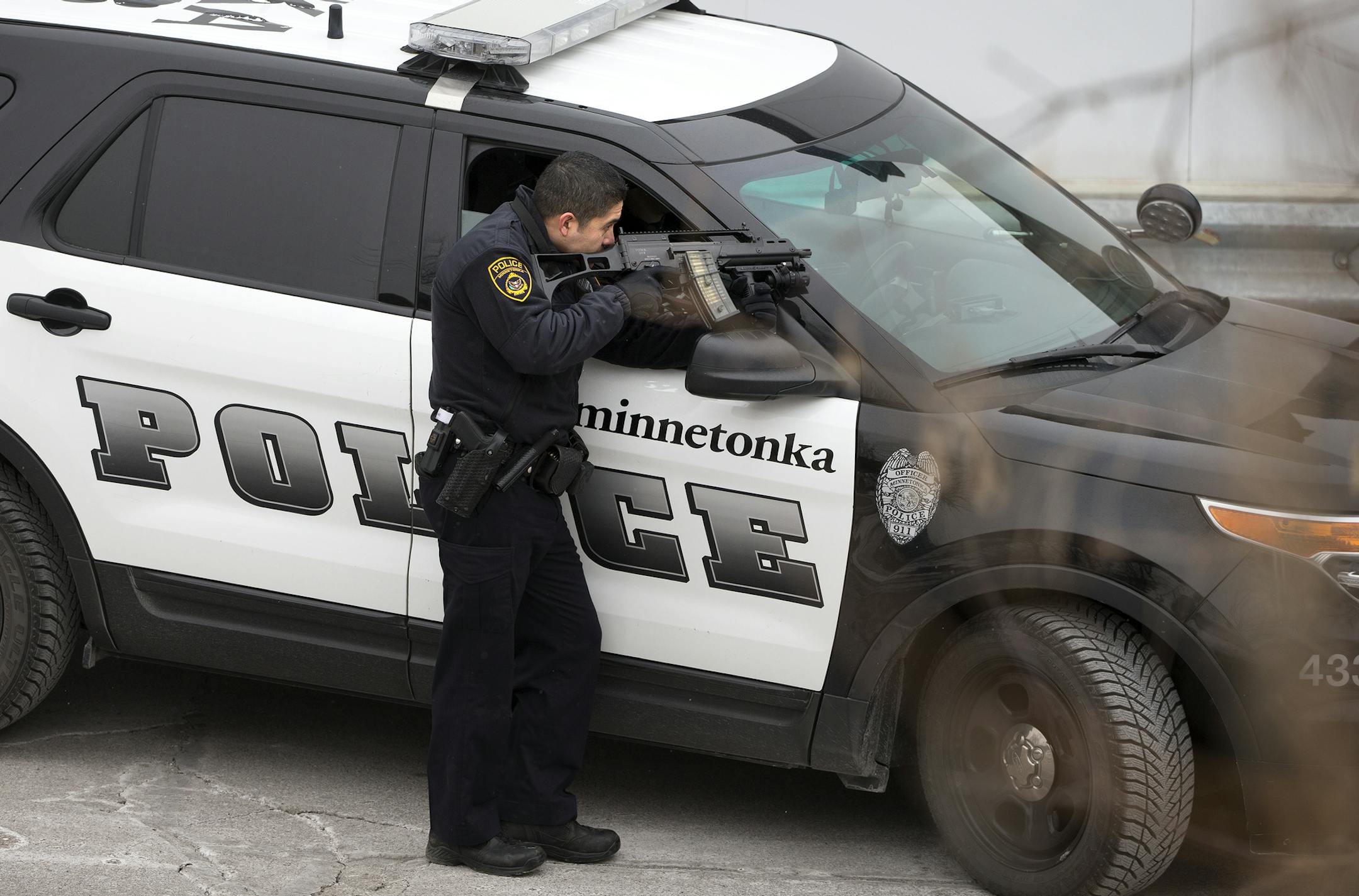 A Minnetonka Police officer points his gun at a side exit of Byerly's in St. Louis Park as part a manhunt following a shootout on Tuesday, February 3, 2015.