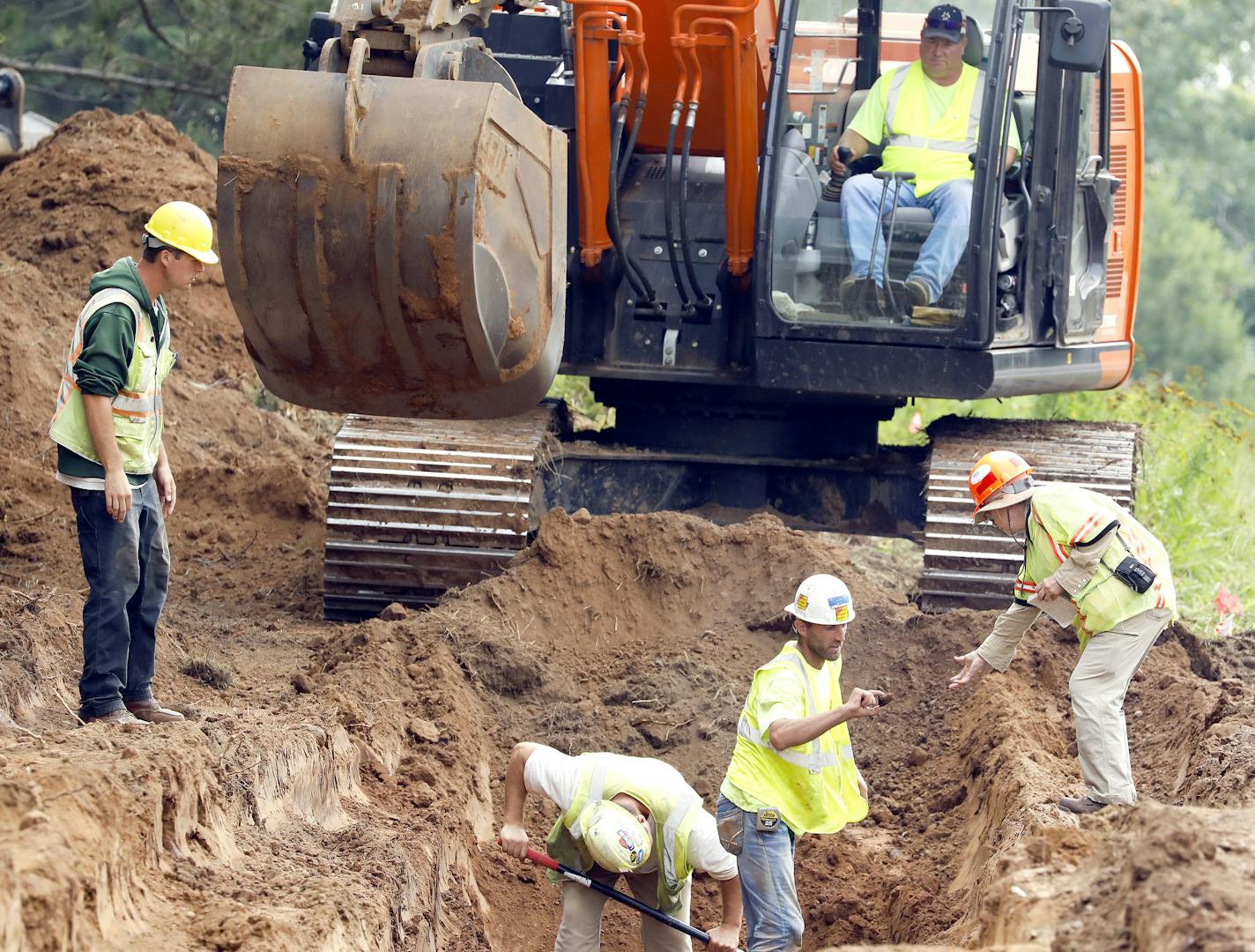 T08.27.2018 -- Steve Kuchera -- 082818.N.DNT.GravesC1 -- A worker hands an object to local archaeologist Susan Mulholland (right) for examination on Monday morning at a excavation site along Arlington Avenue near Arrowhead Road. Last week workers conducting archaeological exploratory digging in preparation for a 2020 road project unearthed wood coffins and what appears to be a human bone.MANDATORY CREDIT: Steve Kuchera / skuchera@duluthnews.com