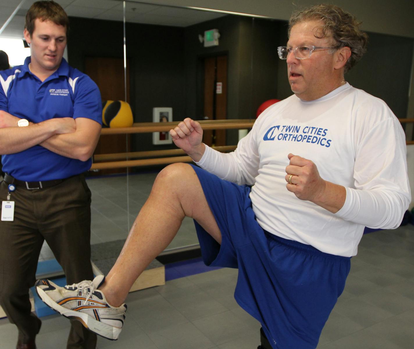 (left to right) Physical Therapist Brandon Schomberg supervised as Dick Golden worked out during physical therapy at Twin Cities Orthopedic in Edina on 8/8/13. Golden got a full knee replacement on his right leg on Jan 15. He wears a brace on his other leg to keept it healthy. The story is about a new program at Twin Cities Orthopedic where patients get one bill and pay one price -- $21,000 -- for knee surgery. Can getting a new knee be as simple as buying a loaf of bread off the shelf? That's t