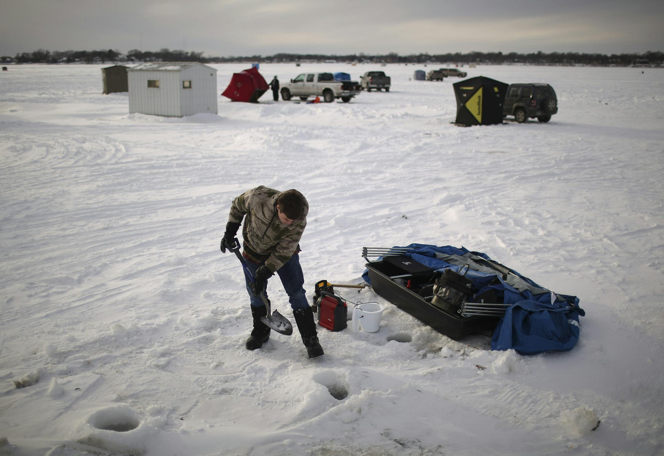 Despite falling temperatures and stiff winds Monday afternoon, January 20, 2014, hard water anglers were out in force north of Bellaire Beach on White Bear Lake. Nick Brevitz of Stillwater cleared an area for his portable ice fishing house to be deployed after dropping a line Monday afternoon. ] JEFF WHEELER • jeff.wheeler@startribune.com