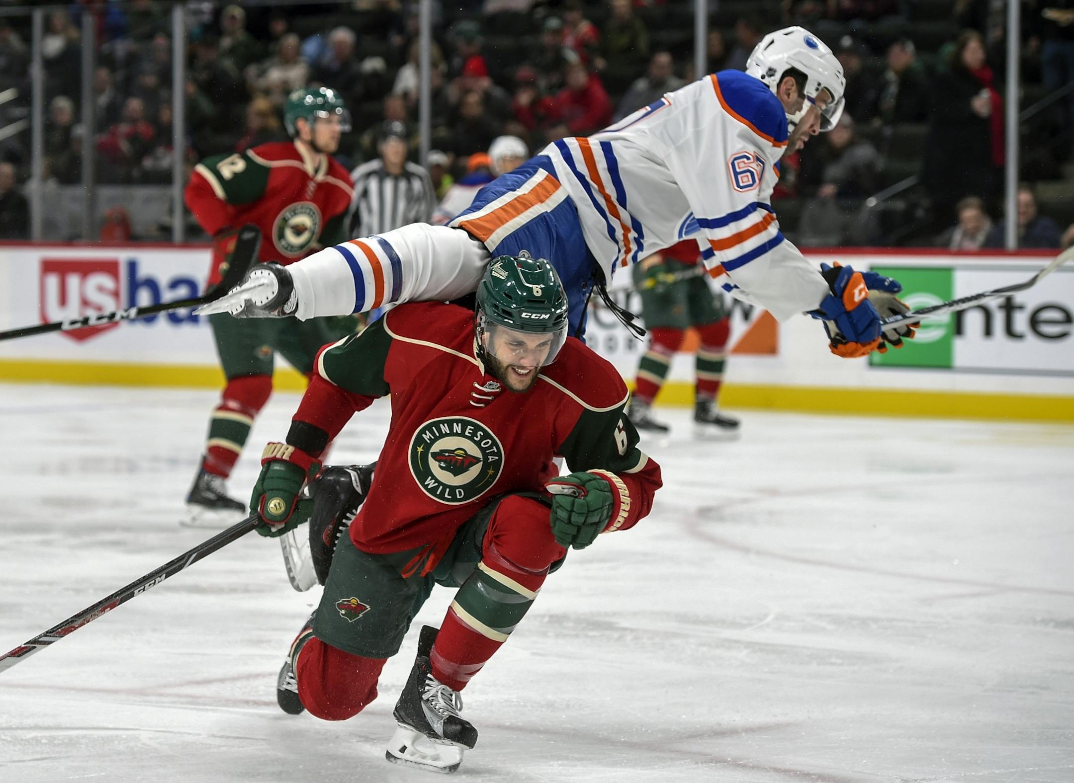 Edmonton Oilers' Benoit Pouliot flies over the top of Minnesota Wild's defenseman Marco Scandella, bottom, during the second period of an NHL hockey game, Friday, Dec. 9, 2016, in St. Paul, Minn.