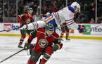 Edmonton Oilers' Benoit Pouliot flies over the top of Minnesota Wild's defenseman Marco Scandella, bottom, during the second period of an NHL hockey g