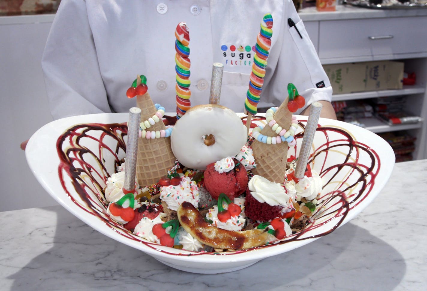 Outta Control: The Sugar Factory in the Mall of America. King Kong Sundae is twenty-four scoops of ice cream, three sauces, sprinkles, graham crackers, gummy bears, marshmallows, Oreos, two waffle cones with candy necklaces hanging from them, gummy cherries, two giant lollipops, a glazed doughnut, a red velvet cupcake and that bruleed banana &#xd0; oh, and two lit sparklersFriday, Dec. 20, 2019, Bloomington, MN. ] Matt Gillmer / matt.gillmer@startribune.com