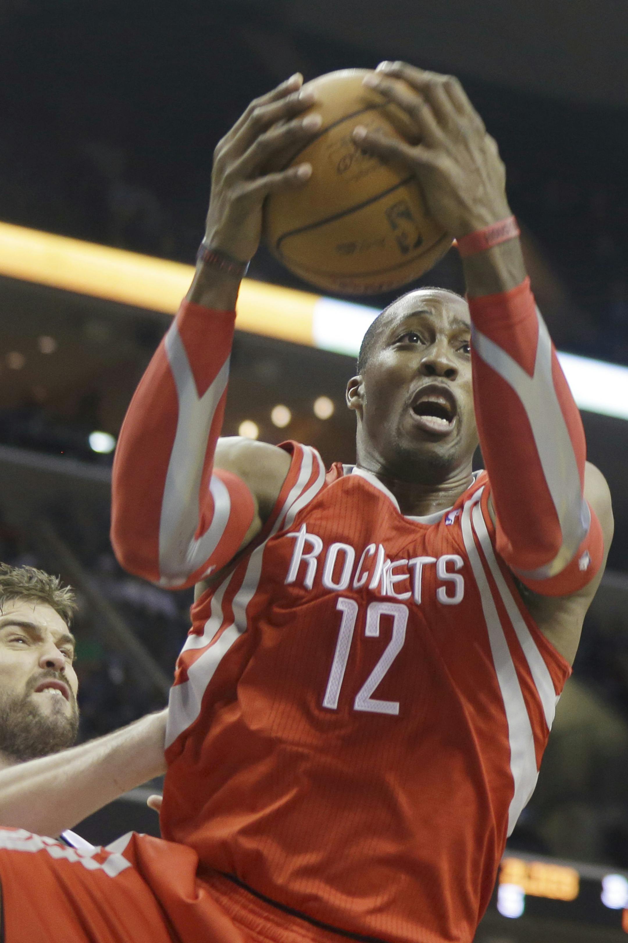 Houston Rockets center Dwight Howard (12) gets a rebound over Memphis Grizzlies center Marc Gasol, of Spain, left, first half of an NBA preseason basketball game in Memphis, Tenn., Friday, Oct. 25, 2013. (AP Photo/Danny Johnston)