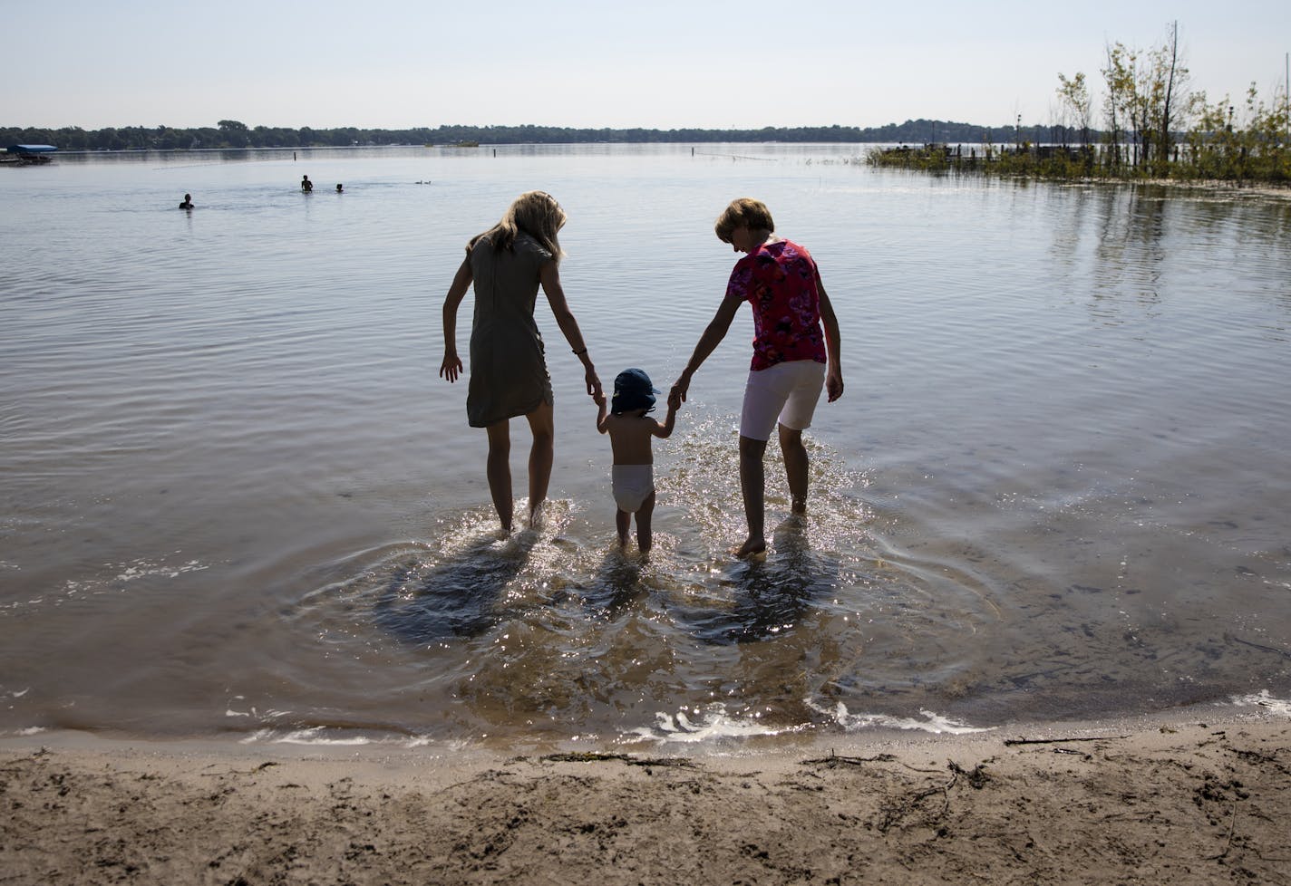 Jennifer Berg her son Miles Berg, 18 months, and her mother Catherine Ellefson walked hand-in-hand into White Bear Lake from Ramsey County Beach in White Bear Lake, Minn., on August 10, 2018. Water levels at White Bear Lake are at a five year high, since turning into a mud puddle in 2013. Ellefson, who used to live blocks from the beach and recently moved back said when she first she saw the beach she said &#x201c;Oh my gosh, it&#x2019;s just like it used to be!" The beach is opened now after be