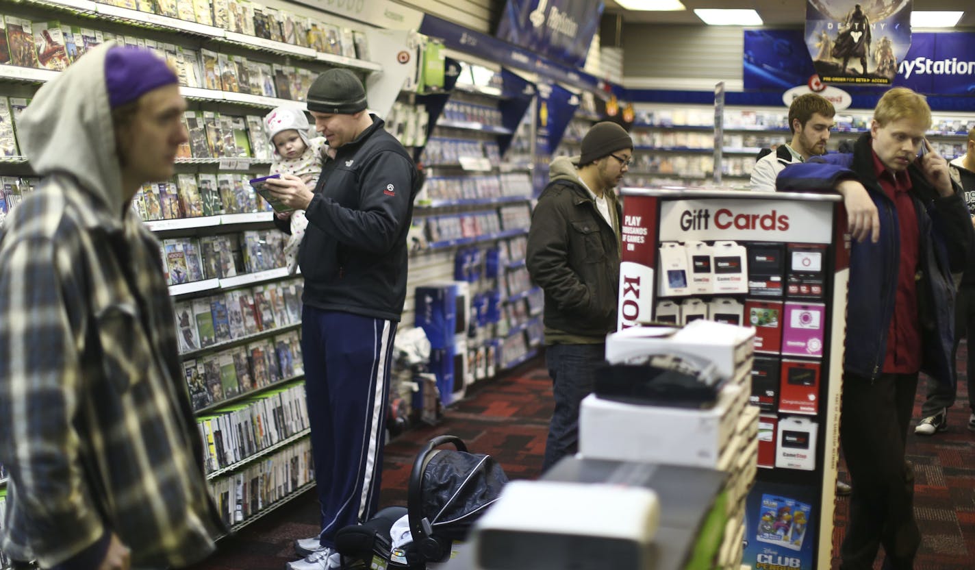 James Silda looked through games with his eight-month old daughter Quinn as he waited in to get a ticket to purchase the new Xbox One later on that night at midnight at Gamestop on Thursday, November 21, 2013 in Roseville, Minn. ] RENEE JONES SCHNEIDER &#x2022; reneejones@startribune.com