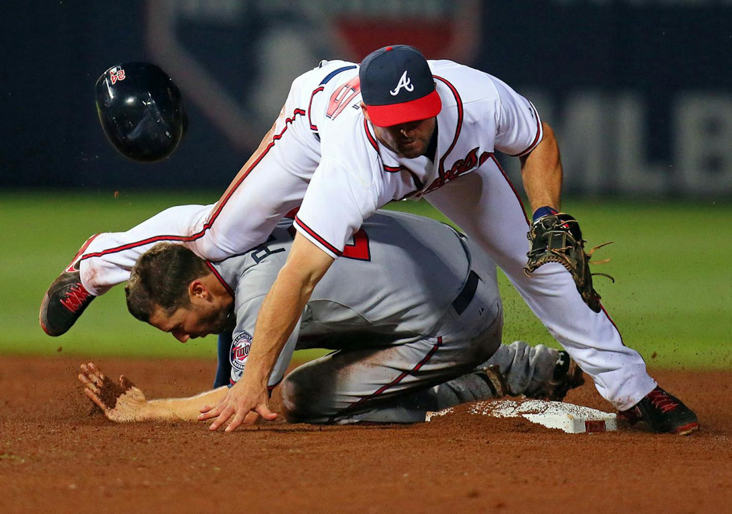 In this Tuesday, May 21, 2013 photo, Minnesota Twins' Trevor Plouffe gets hit in the head by Atlanta Braves second baseman Dan Uggla's shin