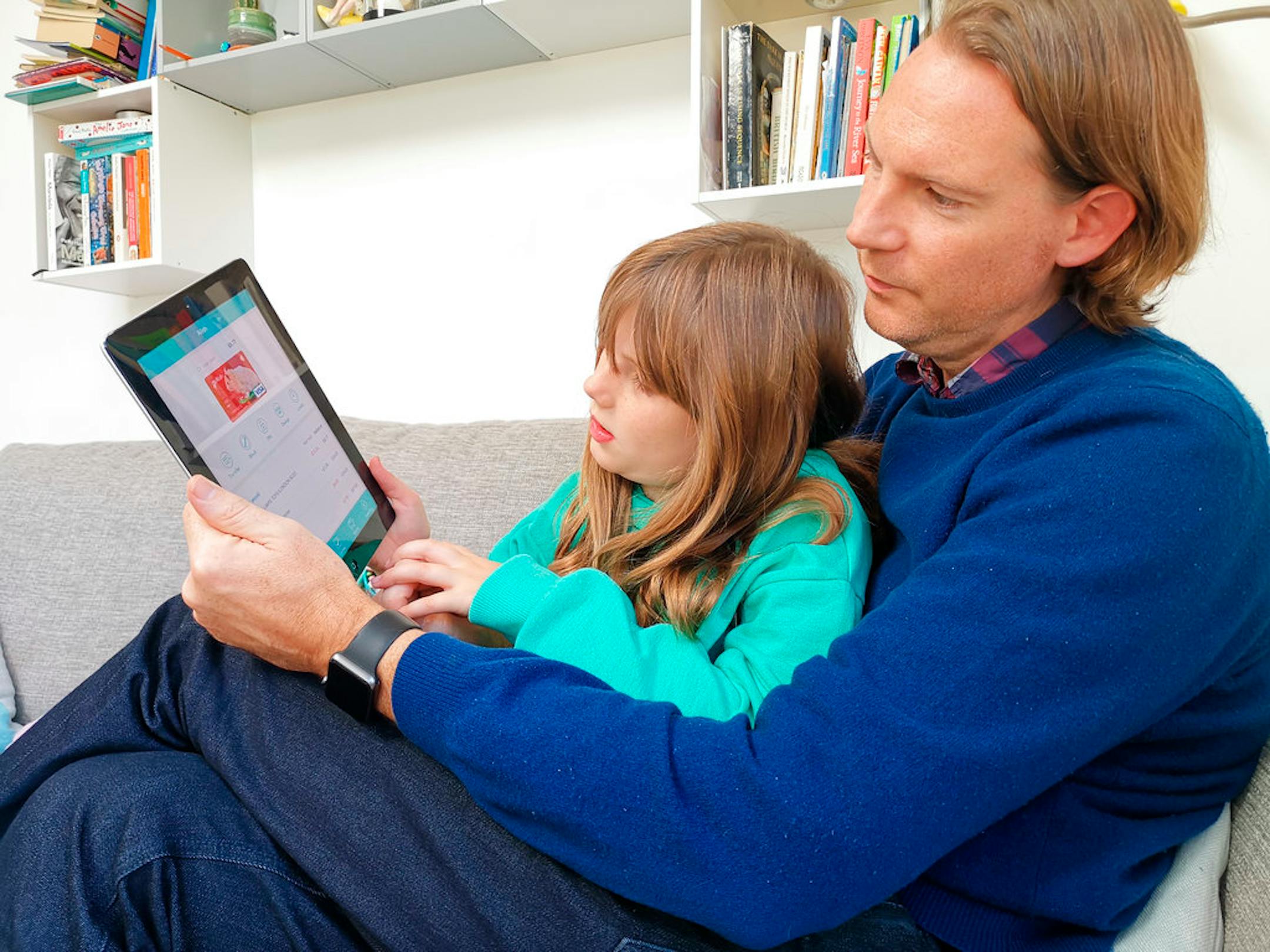 In this photo taken Oct. 21, 2018, Paddy Kelly and his daughter Ailish use Gohenry, one of a wave of digital banking apps for children, in London. A wave of digital pocket money apps that come with prepaid cards are new tools for financial education as money increasingly goes digital, in a shift that's raising uncertainty about how cashless transactions affect youngsters' view of money. (AP Photo/Kelvin Chan)