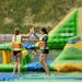 Friends celebrated navigating a floating aquatic obstacle at the Land of Natura, a sprawling new attraction in Wisconsin Dells.