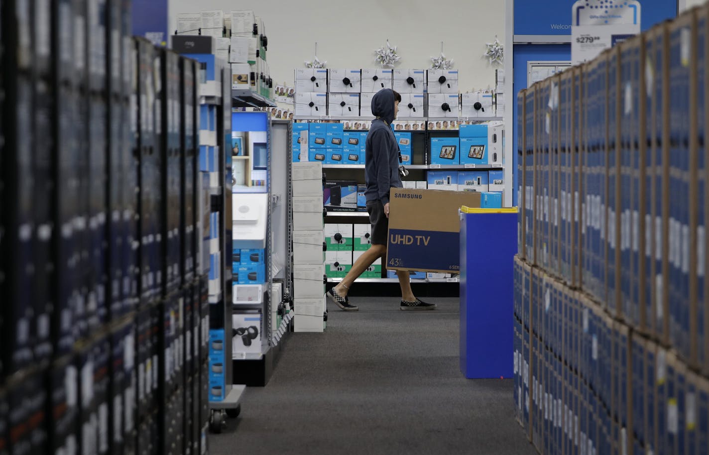 A man carries a television while shopping ahead of Black Friday at a Best Buy, Tuesday, Nov. 26, 2019, in Henderson, Nev. (AP Photo/John Locher)