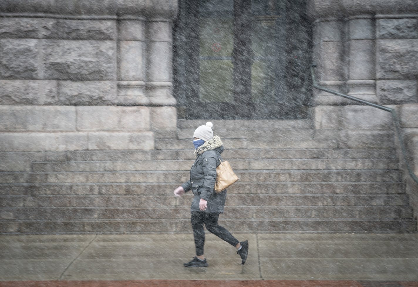 A woman walked through the snow at an empty Government Center light rail stop during the evening rush hour in Minneapolis, on Monday, April 13, 2020.