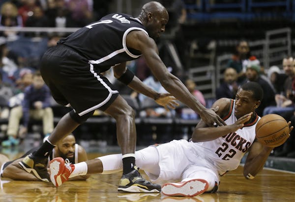 Milwaukee Bucks' Khris Middleton (22) tries to pass the ball with Brooklyn Nets' Kevin Garnett (2) defending during the second half of an NBA basketba