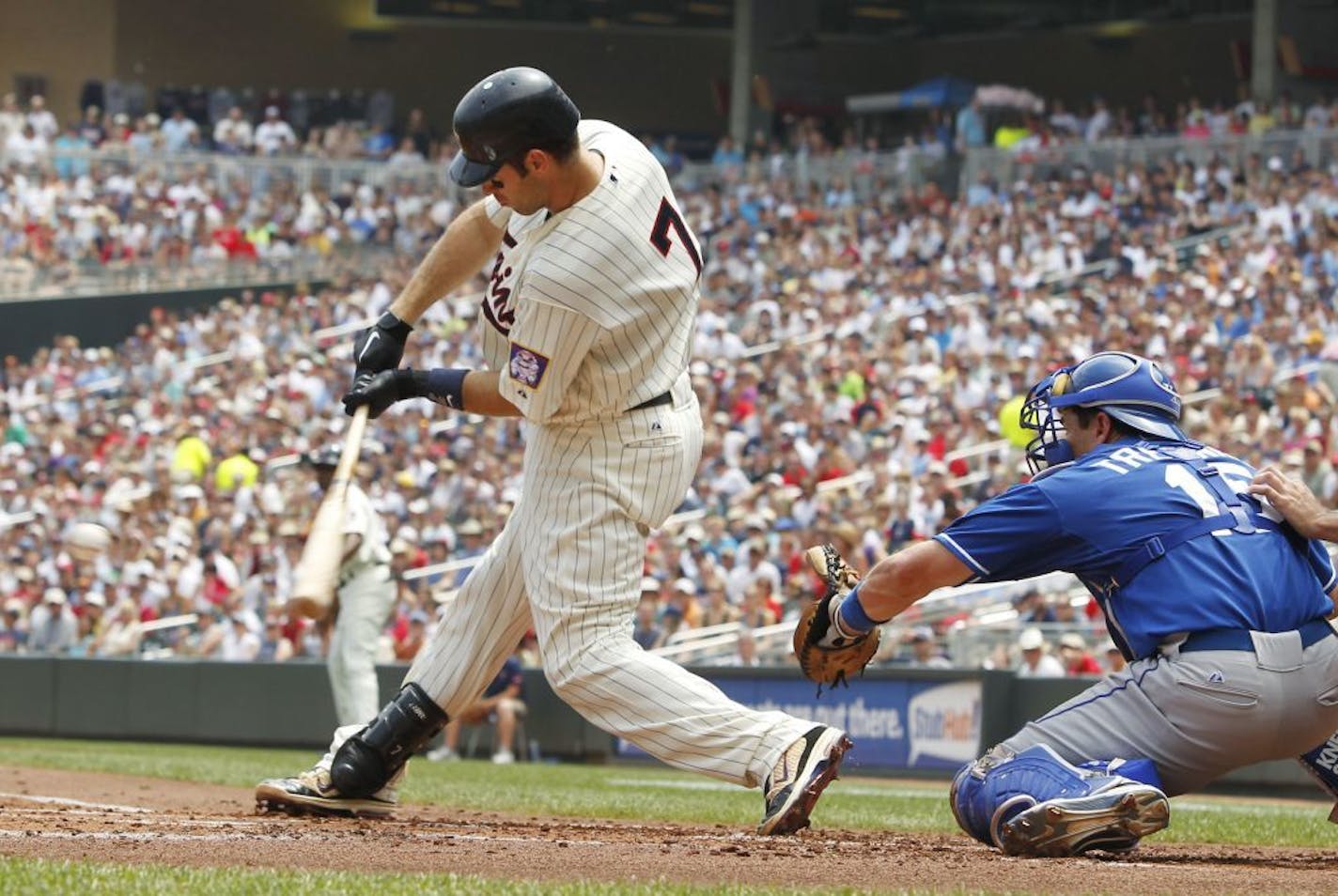 Joe Mauer hits an RBI-single off Kansas City pitcher Felipe Paulino during the first inning nday. At right is Royals catcher Matt Treanor.