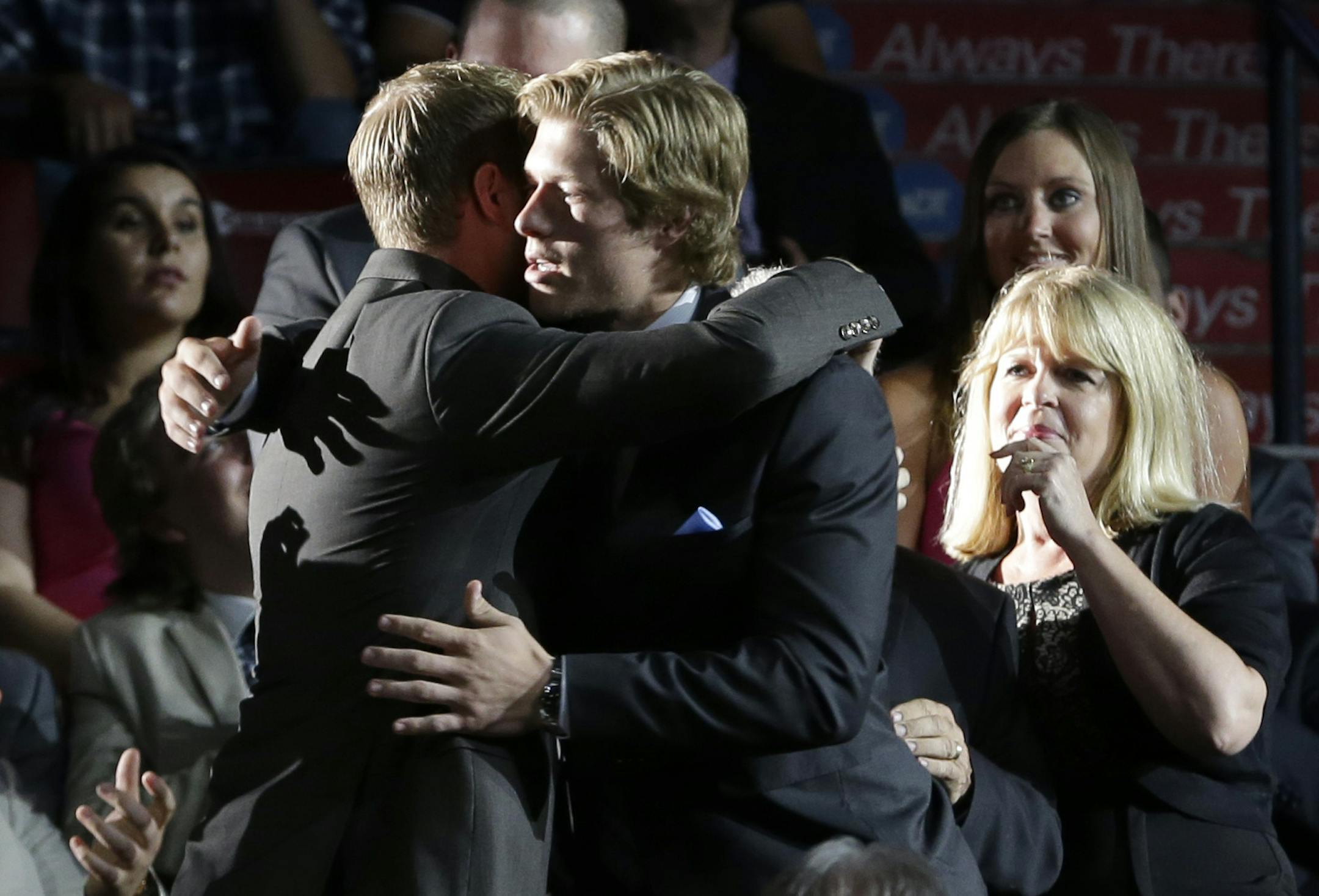 Brock Boeser, center, is hugged as he walks to the stage after being chosen 23rd overall by the Vancouver Canucks during the first round of the NHL hockey draft, Friday, June 26, 2015, in Sunrise, Fla. (AP Photo/Alan Diaz)