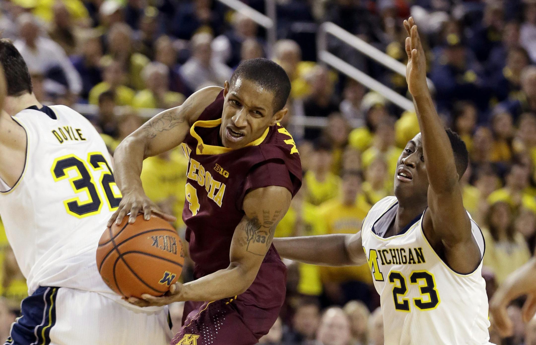 Minnesota guard DeAndre Mathieu looks to pass between Michigan forward Ricky Doyle (32) and guard Caris LeVert (23) during the first half of an NCAA basketball game, Saturday, Jan. 10, 2015, in Ann Arbor, Mich. (AP Photo/Carlos Osorio)