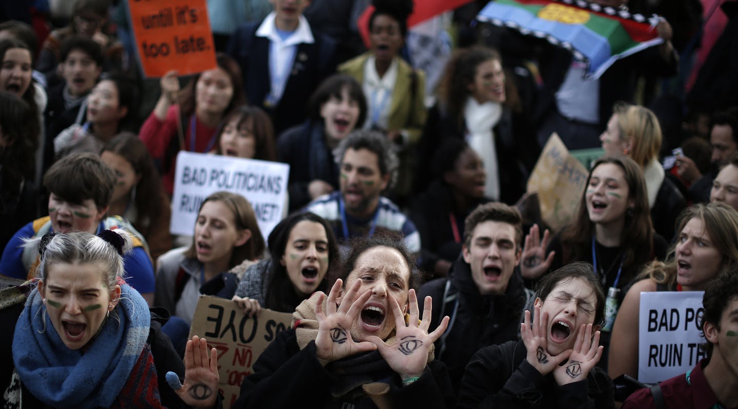 People shout slogans during a march organized by the Fridays for Future international movement of school students outside of the COP25 climate talks congress in Madrid, Spain, Friday, Dec. 13, 2019. The United Nations Secretary-General has warned that failure to tackle global warming could result in economic disaster. (AP Photo/Manu Fernandez)