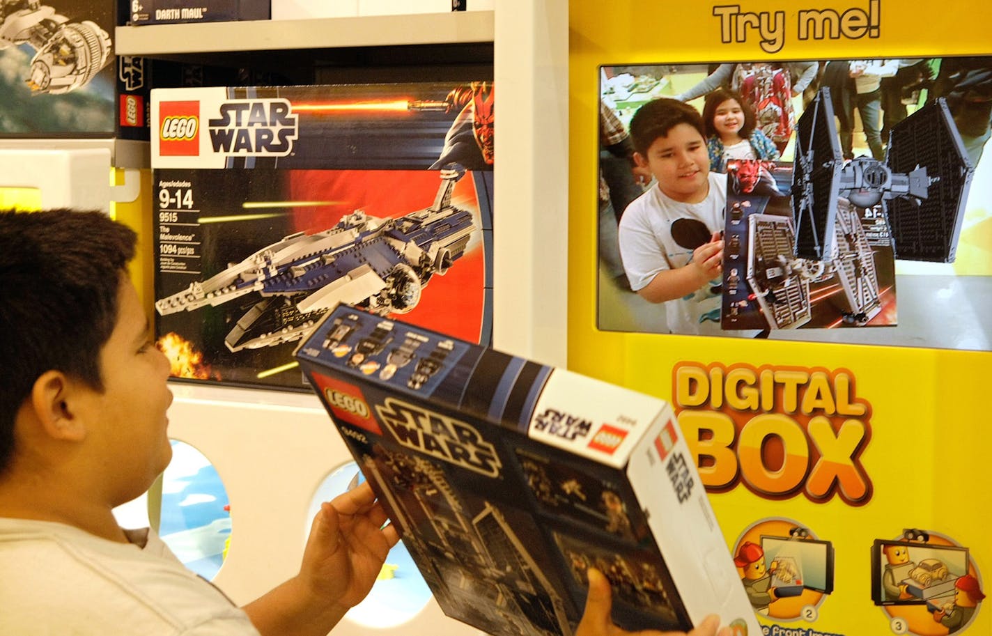 Koby Merlos holds up a Star Wars Lego set to a screen that employs augmented reality technology to bring boxes to life digitally, showing how the sets will look when built on Dec. 20, 2012, in Glendale, Calif. (Mel Melcon/Los Angeles Times/TNS) ORG XMIT: 1218563