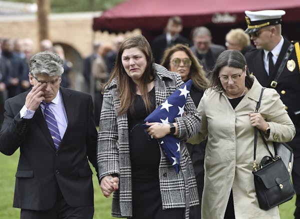 Andrea Parise, center, widow of corrections officer Joseph Parise, leaves his graveside services at Fairview Cemetery in Stillwater, Minn., on Tuesday
