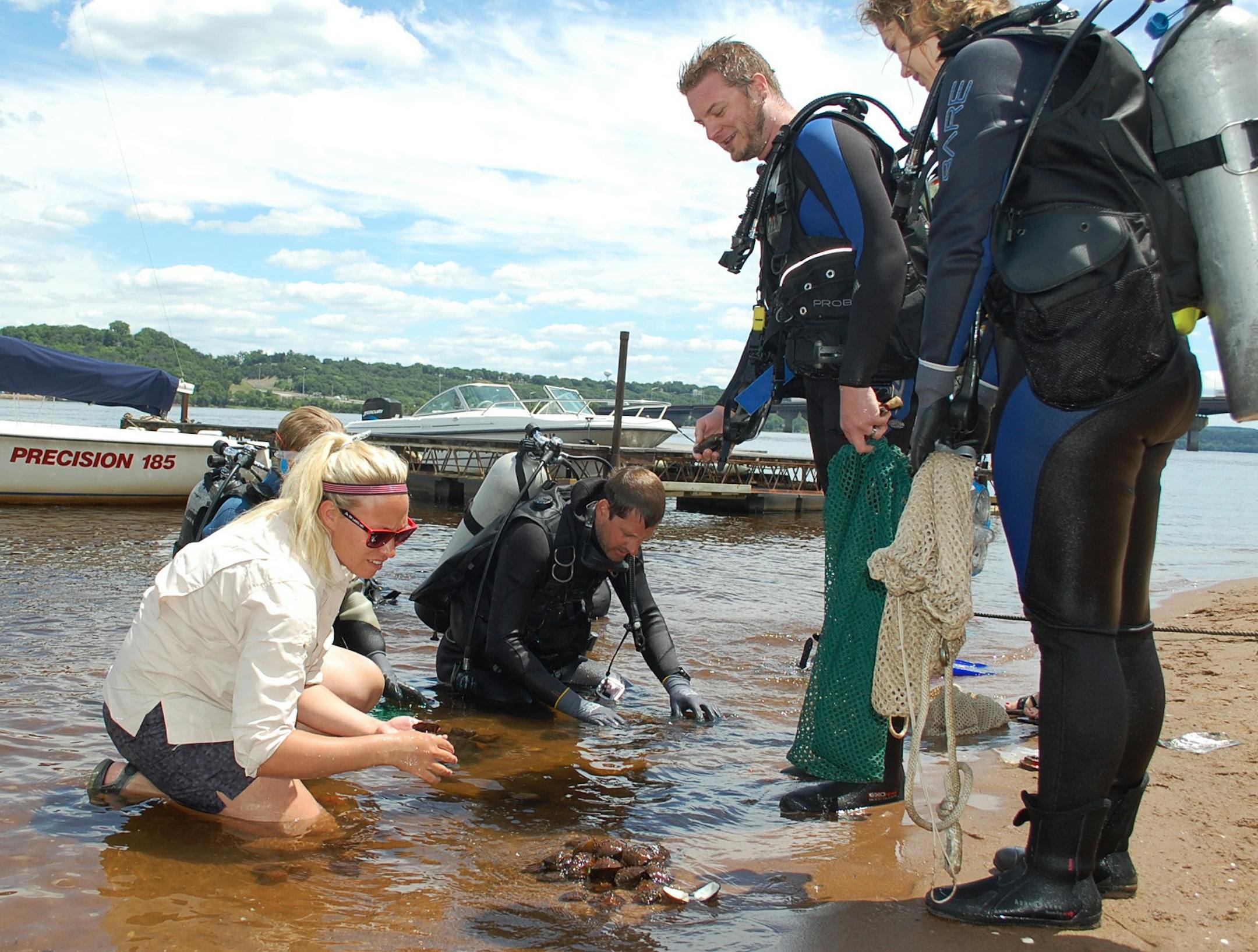 Shelby Marr, left, a natural resources specialist with the Minnesota DNR, helped sort mussels brought up by divers from the Minnesota Zoo on June 29 along the St. Croix River. With her are zoo aquarist Ben Minerich, center, and Wes Schmidt, an aquatic animal life support operator at the zoo.