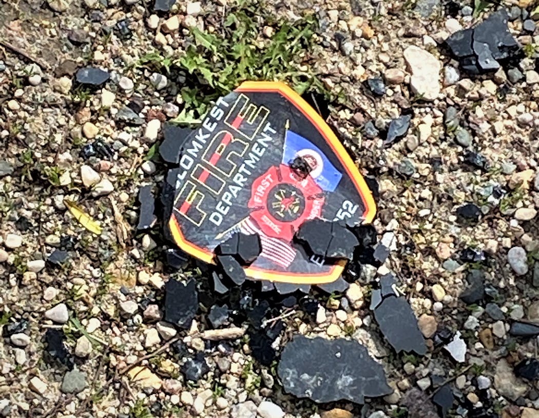 A Blomkest Fire Department sticker sits under shattered glass after the vehicle it was affixed to was crushed by a grain bin that was toppled by high winds. Volunteer firefighter Ryan Erickson was killed in the incident while stationed to watch the severe weather. 