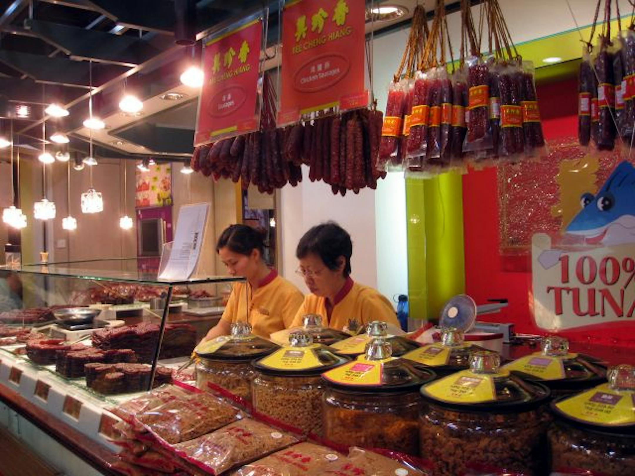 Workers stack slices of chicken, fish and pork jerky (a.k.a. Singapore sausage) in display cases at the Bee Cheng Hiang store near busy Victoria Street.