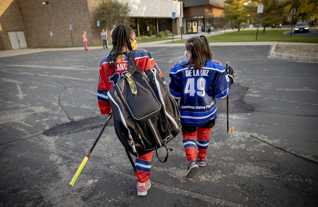 Mia Lang, 9, and Elisa Janzig de la Luz, 8, made their way to hockey practice at the Bloomington Ice Arena.