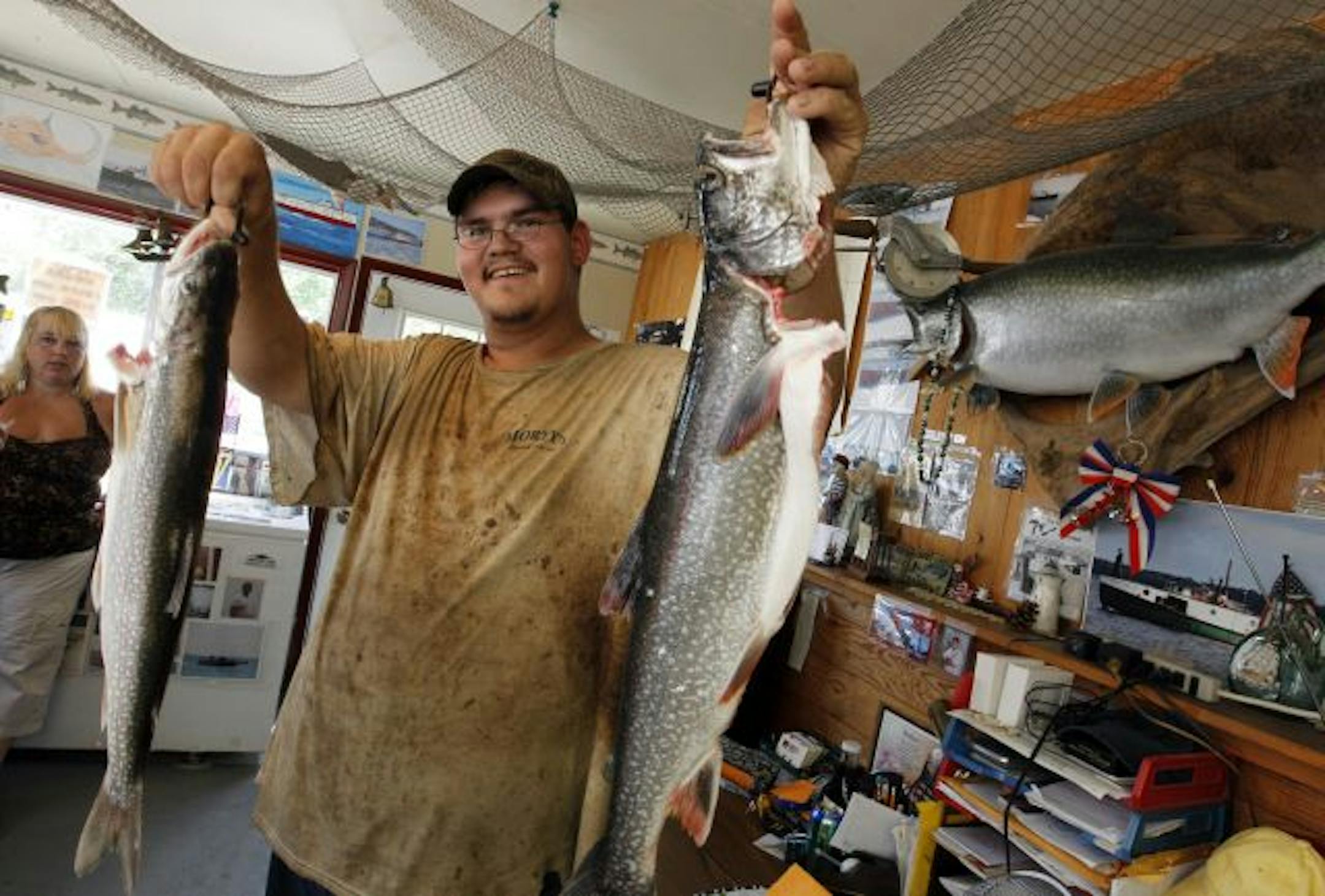 Inside the tiny Newago Fisheries shop, Tanner Bresette shows off part of the day's catch: lake trout.